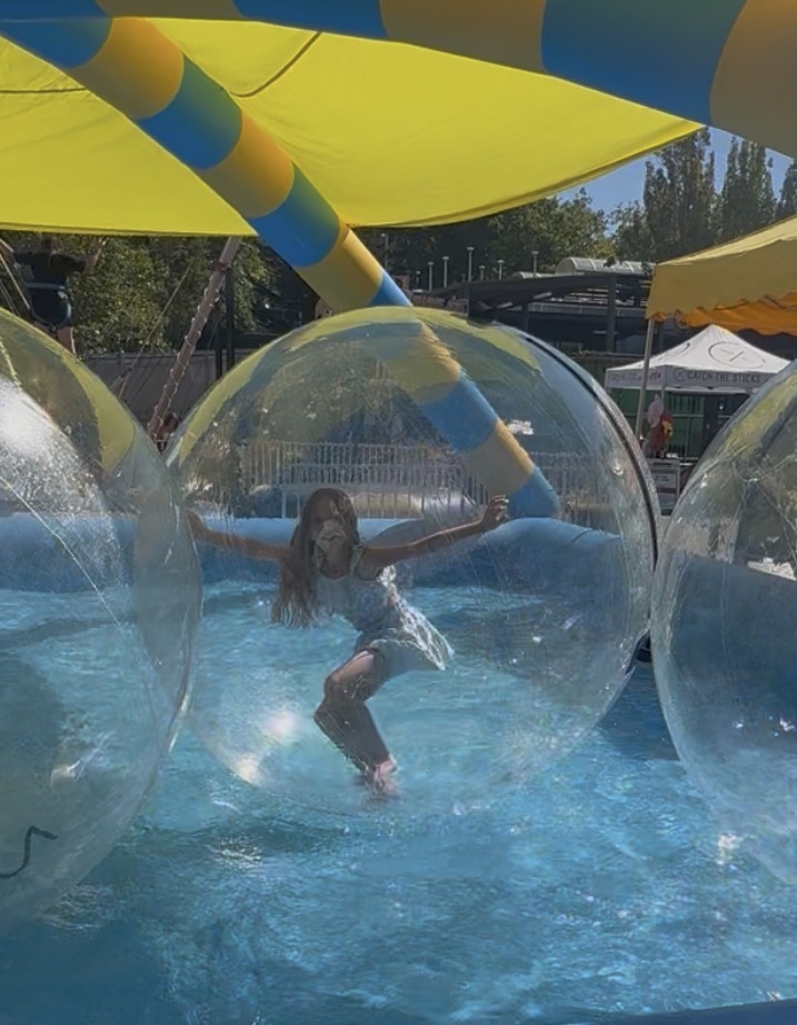 Child playing inside a giant inflatable water walking ball at a sunny outdoor event